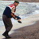 A paramilitary police officer carries the lifeless body of Syrian refugee Alan Kurdi.